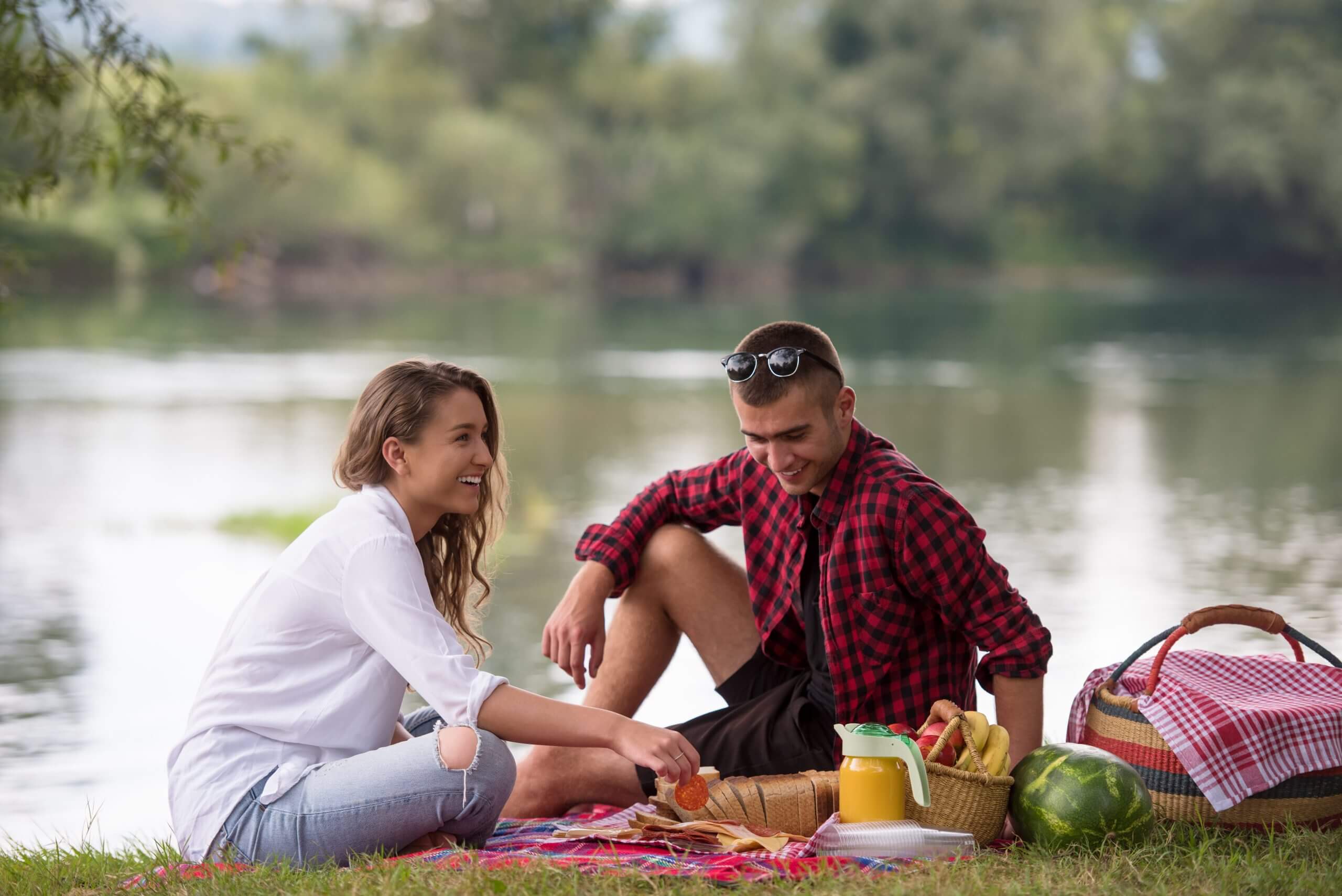 Couple in love enjoying picnic time drink and food in beautiful nature on the lake at Arlo's
